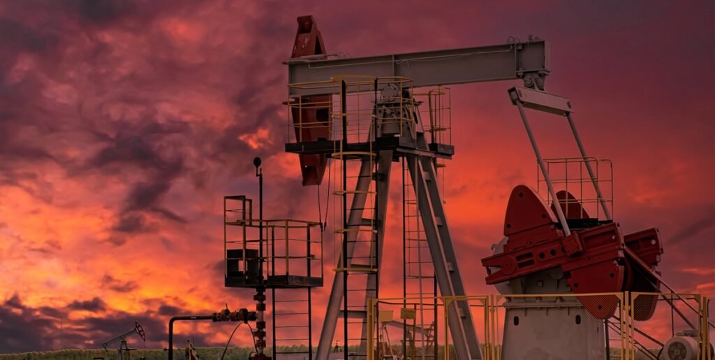 Evaluating oilfield opportunities Oil pump jacks silhouetted against a deep red sunset sky