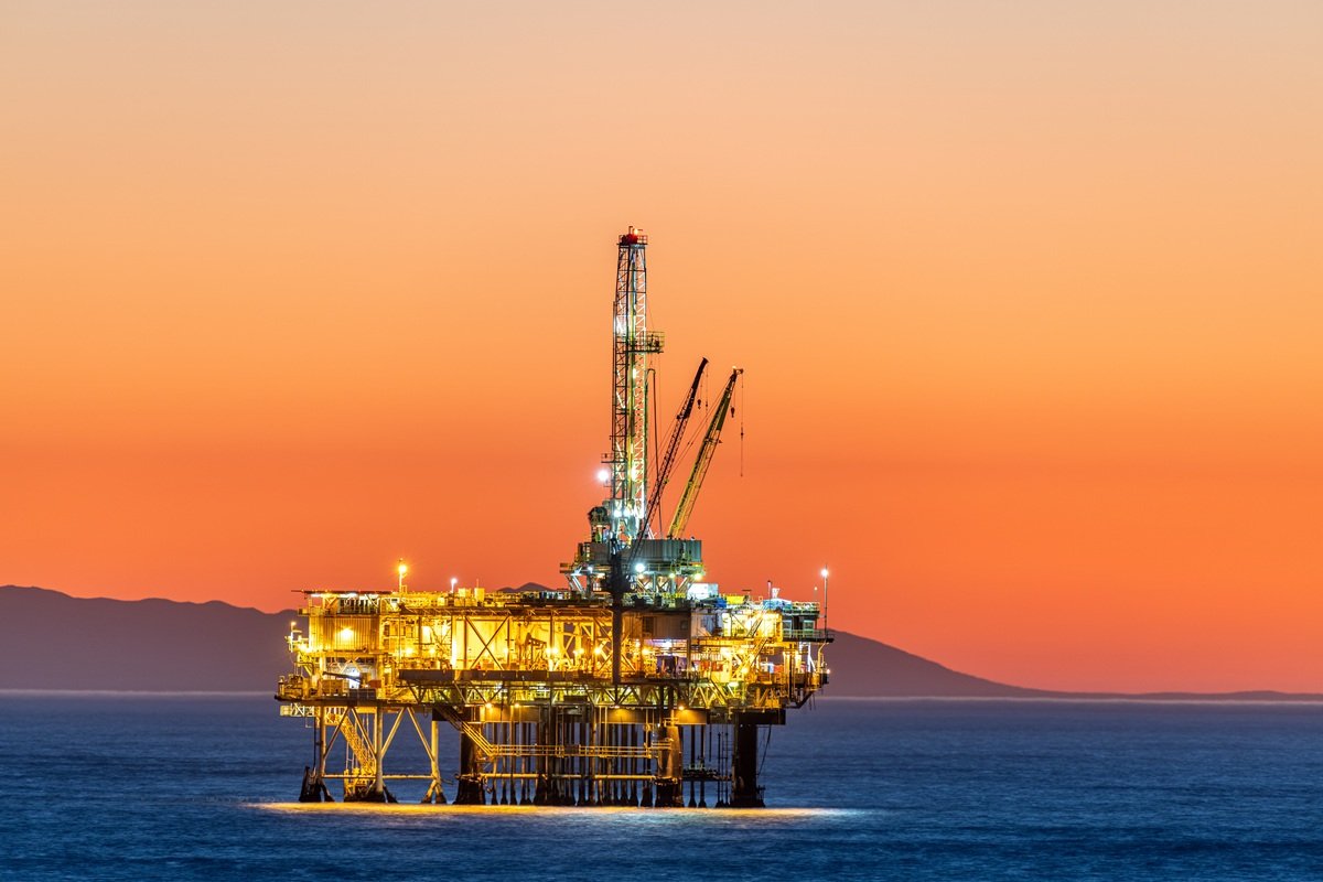 Offshore oil and gas production platform standing in the ocean at sunset