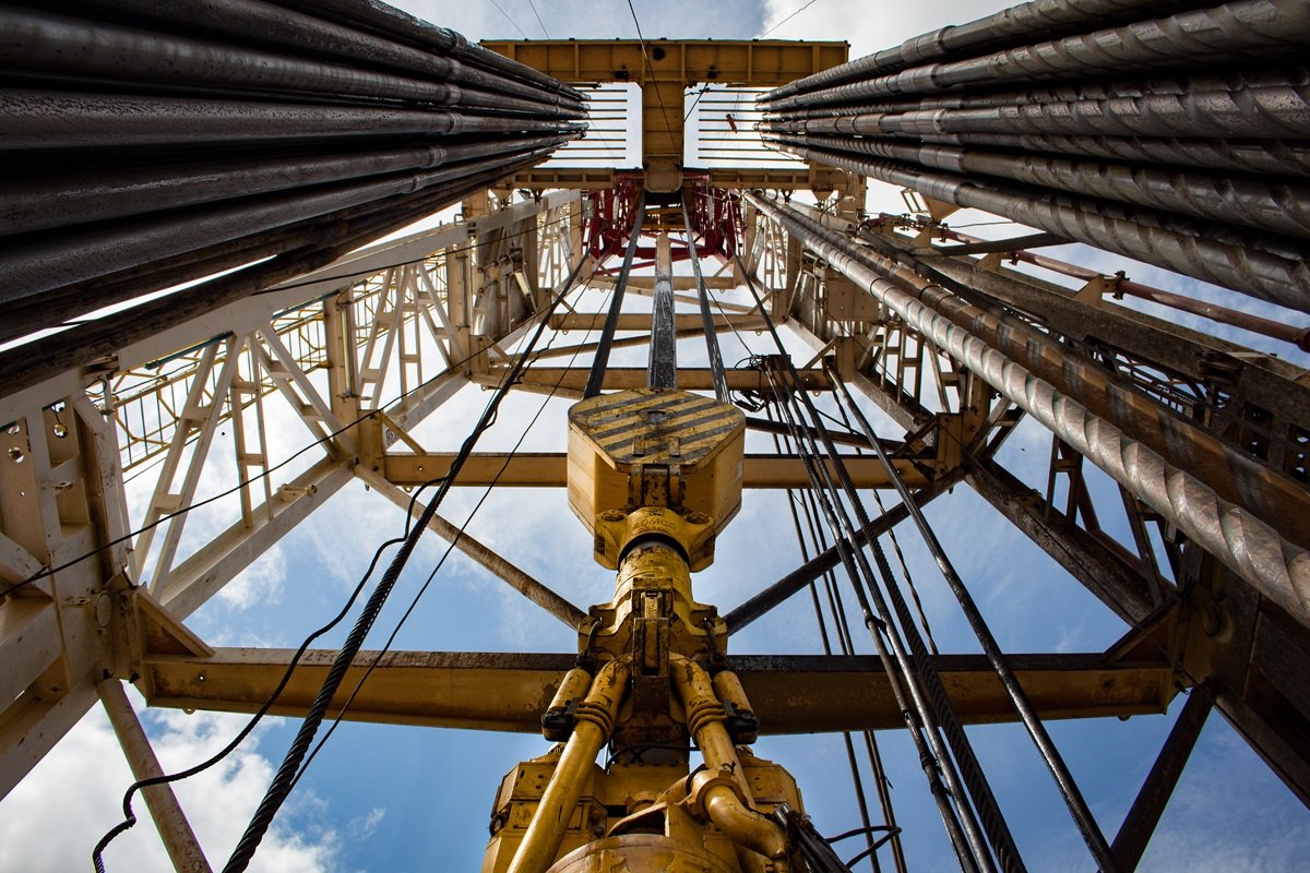 Upward view inside the steel derrick of an oil drilling rig against a clear sky