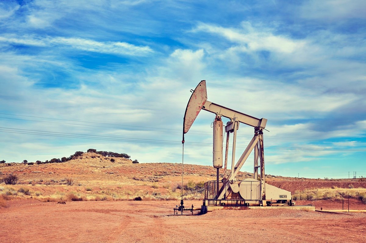 Oil pump jack in the sandy West Texas desert under a blue sky in the Permian Basin