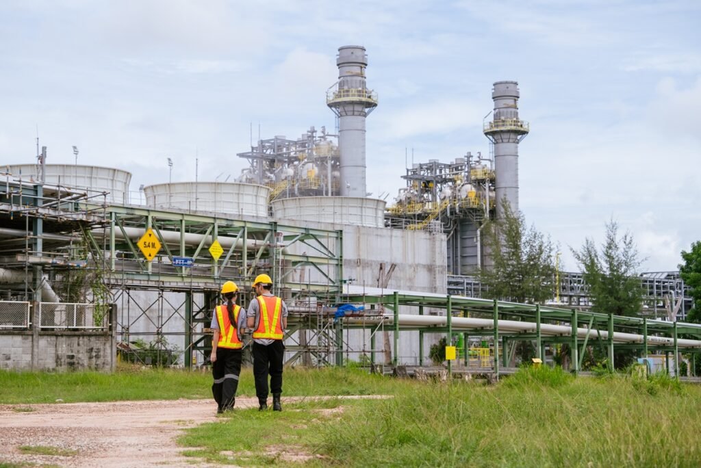 Two workers walking past a natural gas processing facility in the Permian Basin