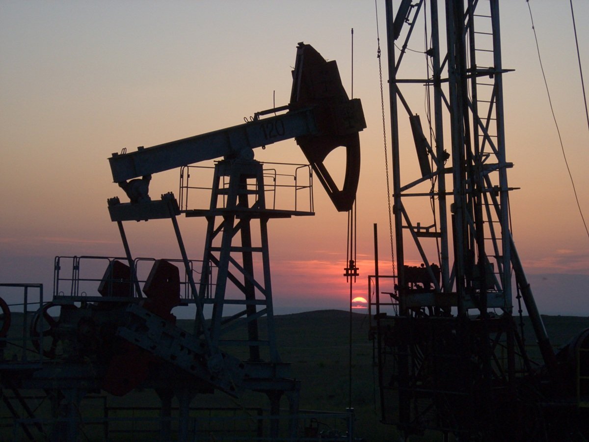 Several oil pump jacks silhouetted against a dusk sky at a U.S. onshore oil and gas field